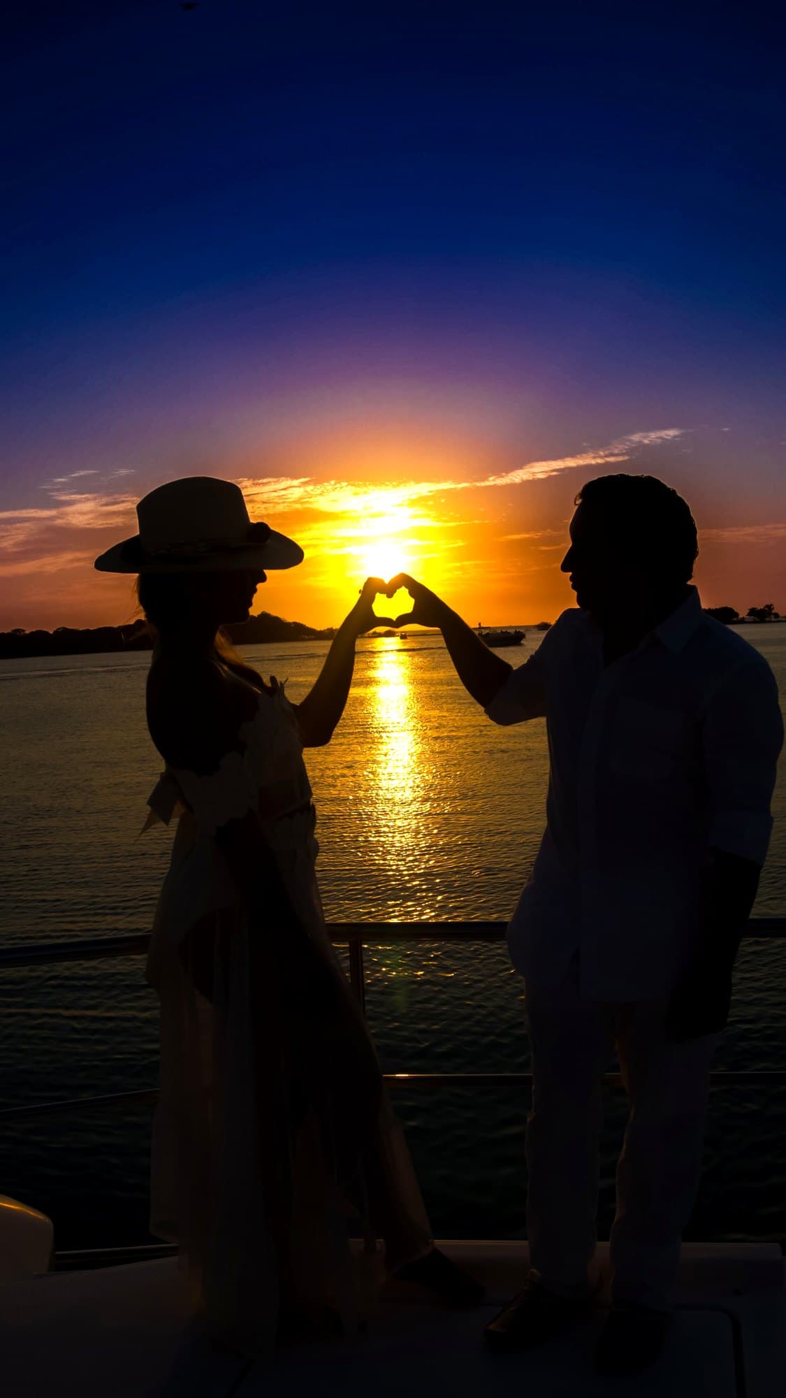 Siluetas de la pareja formando un corazón contra el atardecer