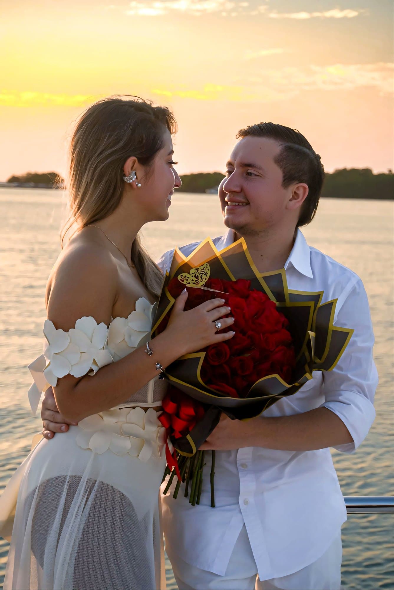 Valentina y Wysler con un ramo de rosas rojas junto al agua