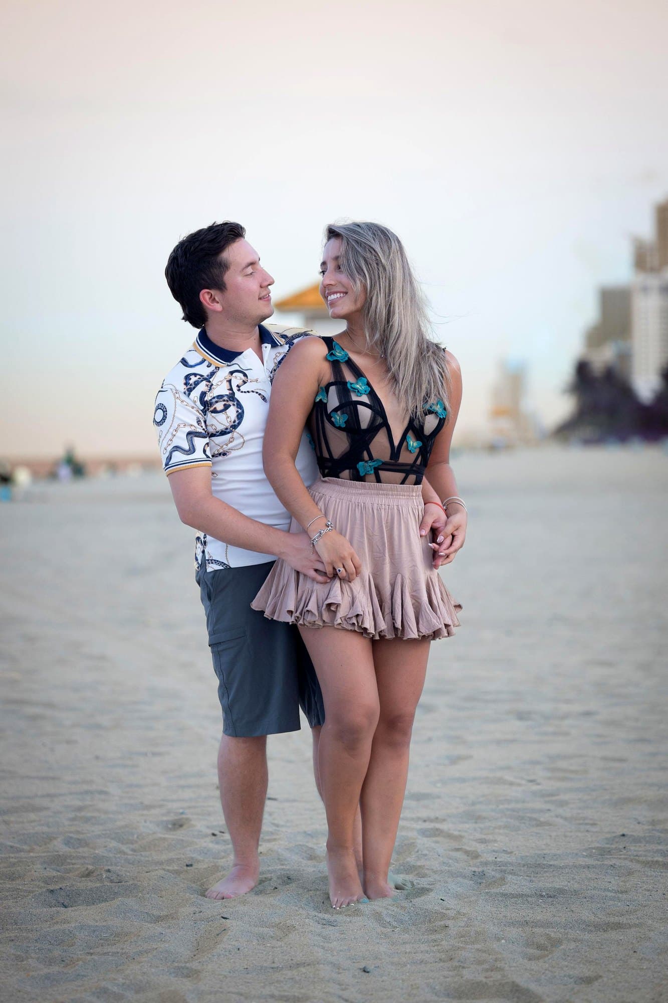 La pareja de pie en la arena, tomados de la mano
